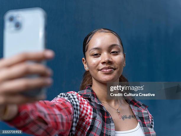 young woman taking selfie against blue wall - fully unbuttoned stock pictures, royalty-free photos & images
