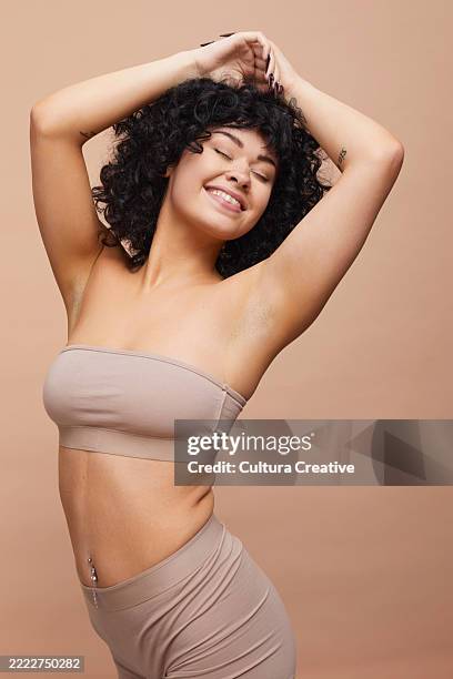 studio portrait of beautiful happy woman with pierced belly button - trägerlos stock-fotos und bilder