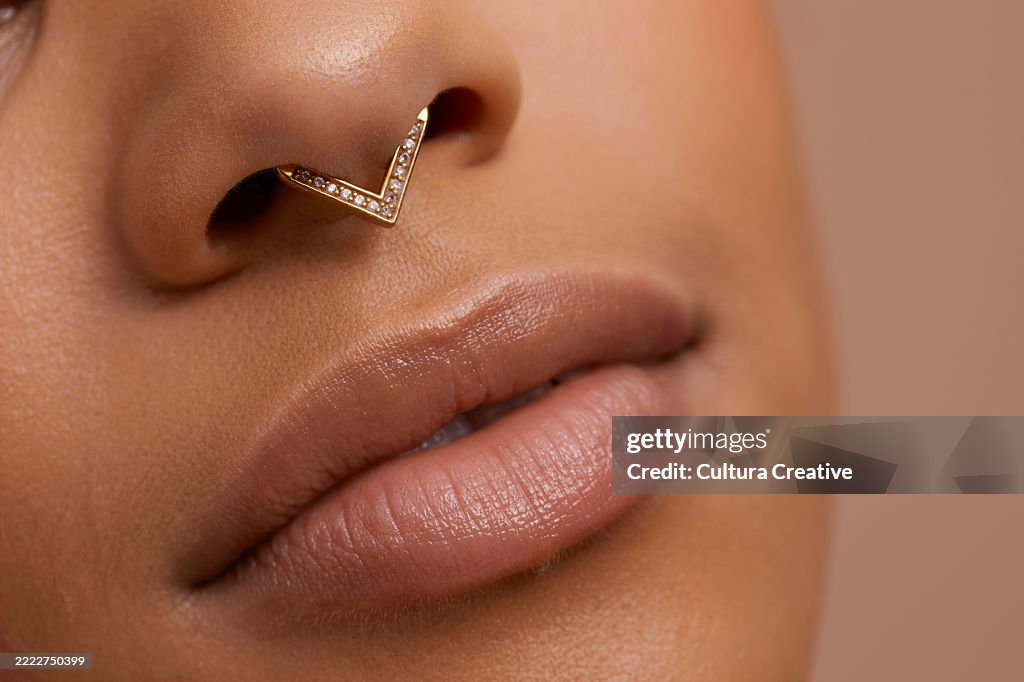 Close up portrait of non binary persons lips and pierced nose
