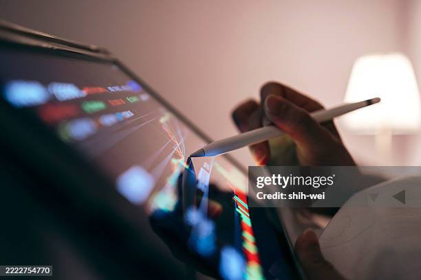 close-up of a woman using a tablet in bed tracking the technical movement of a stock chart on a computer screen. - digitized pen stock pictures, royalty-free photos & images