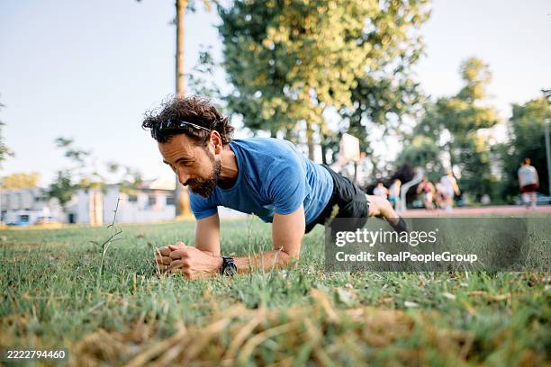 determined athlete performing plank exercise in park - man plank exercise stock pictures, royalty-free photos & images