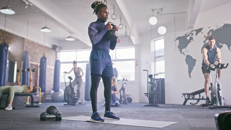 https://media.gettyimages.com/id/2222893216/video/young-man-performing-kettlebell-squats-in-a-lively-gym-setting-with-diverse-people-exercising.jpg?b=1&s=640x640&k=20&c=MbI_p5tK4p1GKNNCRrnifzs1AXq_Jwx2pV_EtWBH_VI=