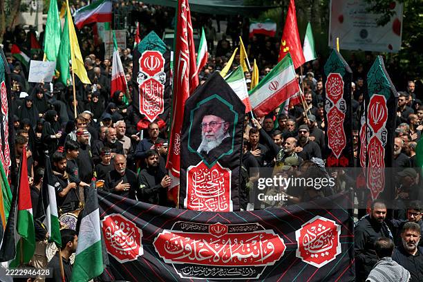 Iranians carry a banner bearing the images of supreme leader Ayatollah Ali Khamenei during a rally in his support, as Shiite Muslims attend the...