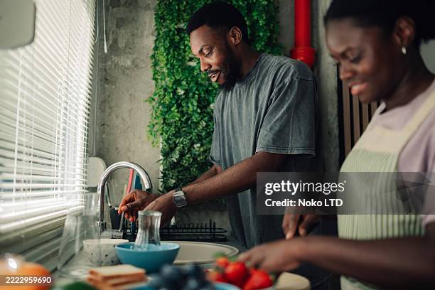 couple washing dishes and preparing food in kitchen - kitchen sink stock pictures, royalty-free photos & images
