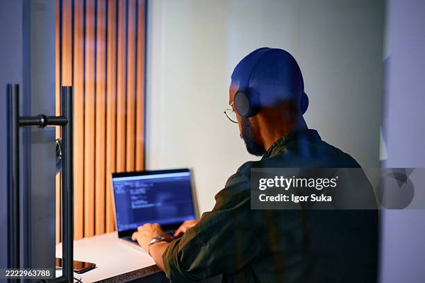 focused programmer working on code late at night in the office - warm light stock pictures, royalty-free photos & images