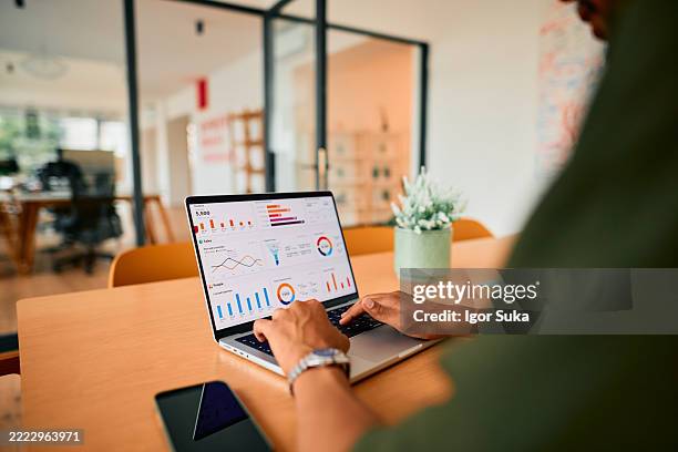 businessman analyzing financial data on laptop in modern office - marktonderzoek stockfoto's en -beelden
