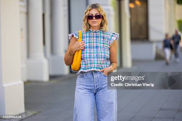Aline Kaplan wears blue pink striped sleeveless top Sezane, washed out light jeans Agolde, orange bag Bagllet during Berlin Fashion Week -...