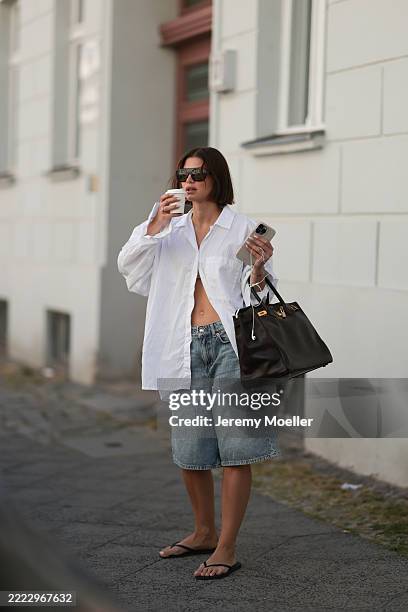 Sophia Geiss is seen wearing a silver nose ring, black aviator sunglasses from Vehla Eyewear, an oversized white structured shirt from Black Palms,...