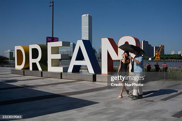 Couple with an umbrella is seen at West Bund in Shanghai, China, on July 5 as the temperature reaches 38 degrees Celsius.