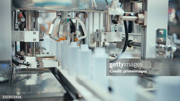 produktionslinie für pharmazeutische oder kosmetische produkte mit automatisiertem spender für kleine plastikflaschen | präzisions-flüssigkeitsabfüllsystem in moderner industrieller verpackungsmaschine - chemikalie stock-fotos und bilder