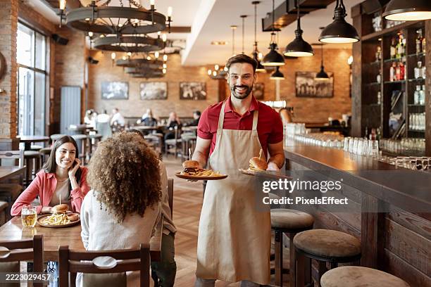 lo mejor de la hospitalidad: camarero con hamburguesa y papas fritas - camarero fotografías e imágenes de stock