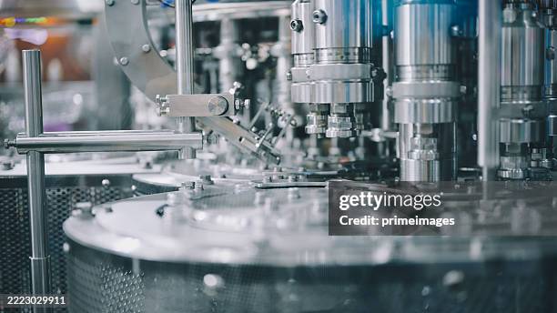 sistema automatizzato di riempimento di liquidi ad alta velocità con testa rotante multi-ugello macchina in linea di produzione industriale per il processo di confezionamento di liquidi con meccanismo in acciaio inossidabile e controllo di precisione - riempire foto e immagini stock