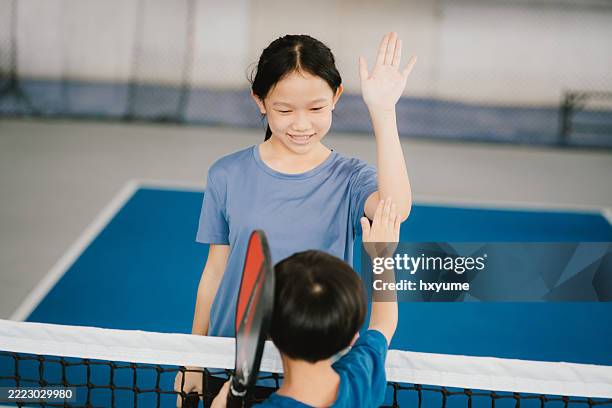 asiatisches geschwisterkind feiert nach einem pickleball-spiel - mittleres kindesalter stock-fotos und bilder