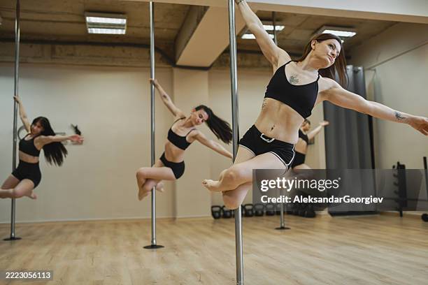 strong female dancers synchronously mastering pole climb and spin skills during intense group practice - pole dancer stock pictures, royalty-free photos & images