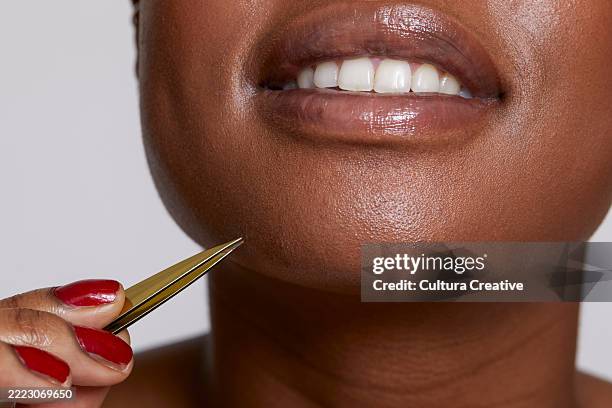 close-up of smiling woman with tweezers - tweezers stock pictures, royalty-free photos & images