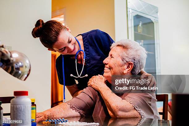 female nurse and senior woman talking at home - house call stock pictures, royalty-free photos & images