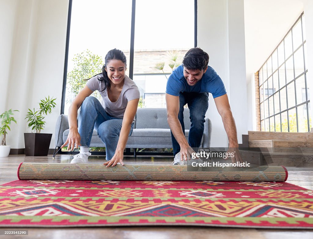 Couple déroulant un nouveau tapis lors d’un déménagement
