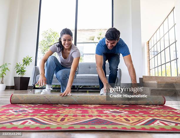 couple déroulant un nouveau tapis lors d’un déménagement - tapis décoratif photos et images de collection
