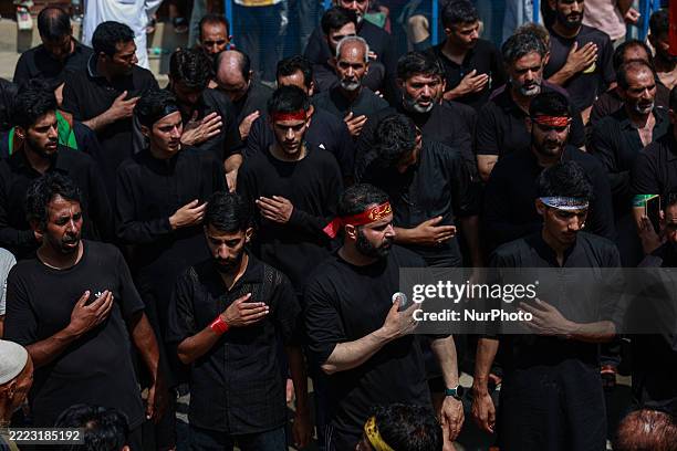 Kashmiri Shiite Muslims hold placards of Ali Khamenei in solidarity with Palestinians and Iran during a religious procession to mark Ashura, on the...