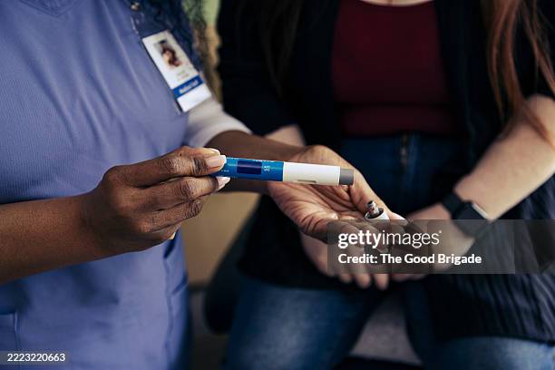 hand of female nurse holding weight loss injection pen in exam room at doctor's office - fazer dieta imagens e fotografias de stock