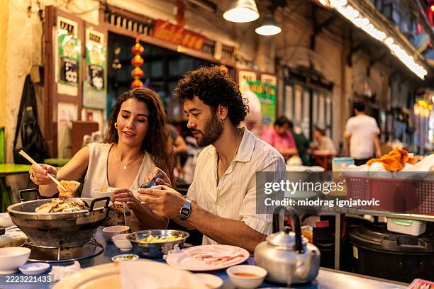couple profitant d’un dîner chaud confortable côte à côte - cuisine thaïlandaise photos et images de collection