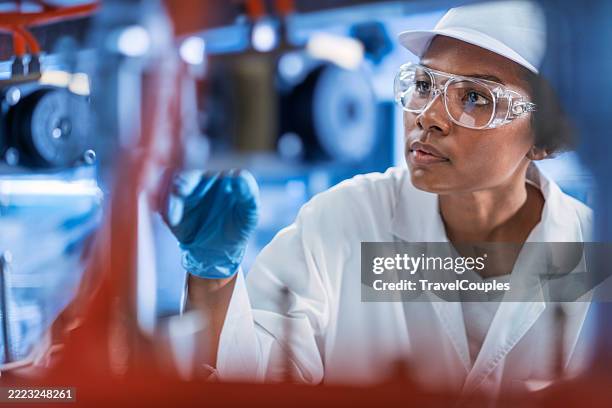 woman engineer in a drinking water factory in professional uniform using digital tablet working in beverage industrial. female worker scientist with laboratory inspect quality of drinking water inside of the production line factory while using digital tab - produktionsgerät stock-fotos und bilder