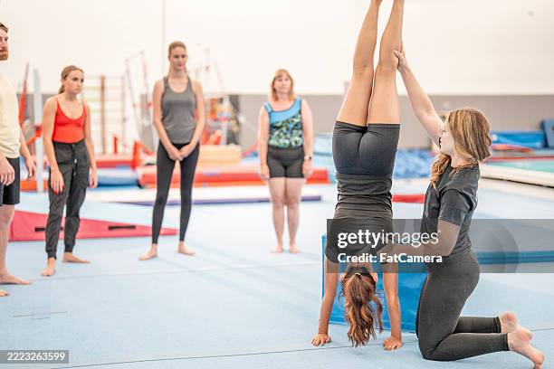 group training in gymnastics skills with instructor assisting - acrobatic activity stock pictures, royalty-free photos & images