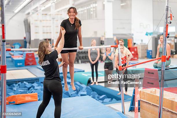 gymnastics training session with coach and student practicing bars - turnen stockfoto's en -beelden