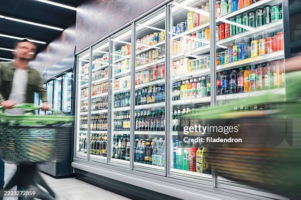 busy customers pushing shopping cart at the supermarket - refrigerated section supermarket stock pictures, royalty-free photos & images