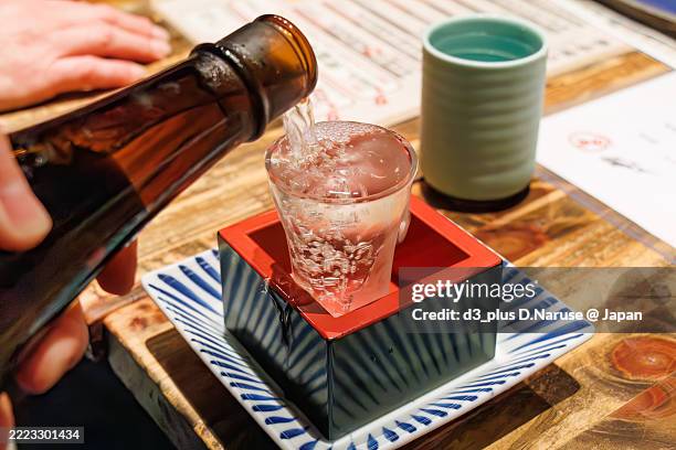 we drink isojiman, a daiginjo from shizuoka pref.the glass, masu, and plate are filled to the brim. - sake stock-fotos und bilder