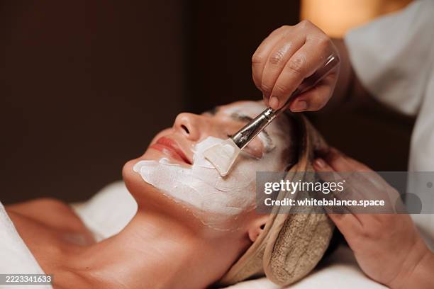 woman receiving a rejuvenating facial mask treatment from a skilled professional at a health and wellness center - spa bildbanksfoton och bilder