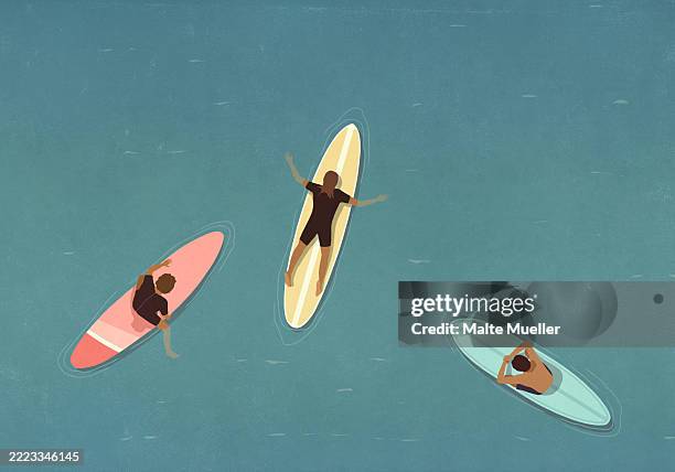 view from above of surfers laying on surfboards in ocean - woman surfing stock illustrations