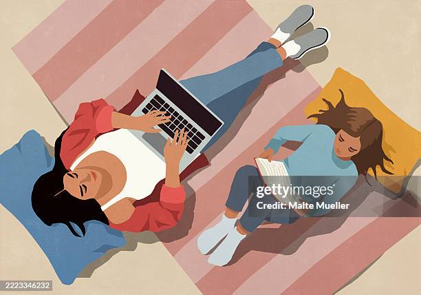 view from above of mother working at laptop next to daughter reading book on floor at home - daughter stock illustrations