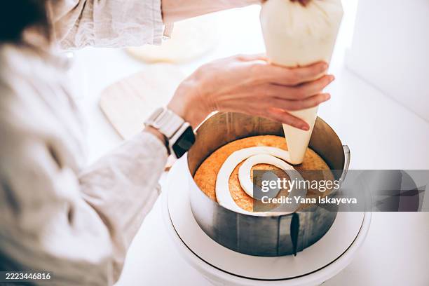 person decorating a cake with icing in a baking tin using a piping bag - decorating a cake stock pictures, royalty-free photos & images