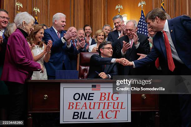 Speaker of the House Mike Johnson is congratulated by his fellow Republicans after signing the One Big Beautiful Bill Act during an enrollment...