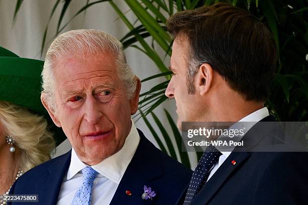 French President Emmanuel Macron speaks to King Charles III, whose eye is red, during a welcome ceremony at Windsor Castle as part of Macron's state...