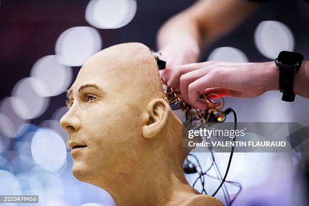 Man works on the electronics of Jules, a humanoid robot from Hanson Robotics that uses artificial intelligence, at a stand during the International...