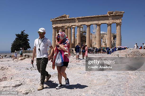 Tourists walk in front of the Parthenon temple, during a heatwave in Athens, Greece on July 8, 2025.