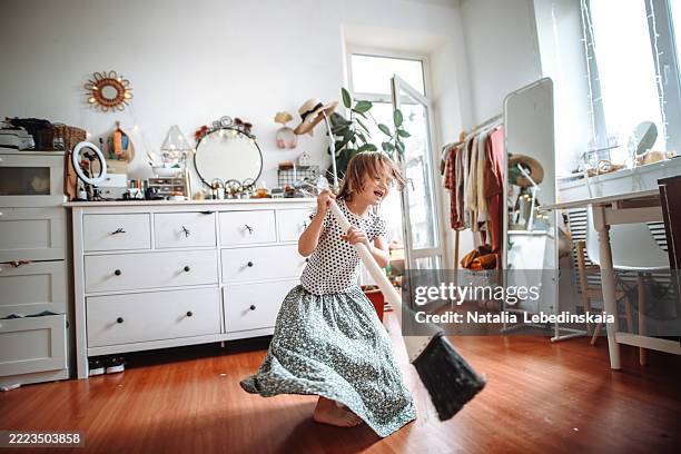 caring for the home: child girl in a long skirt finds happiness in cleaning and helping with a broom. - chambre bien rangée photos et images de collection