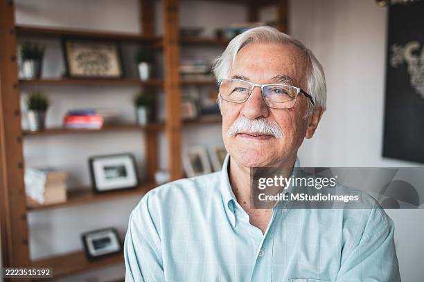 senior man relaxing in cozy home library - 70s mustache stock pictures, royalty-free photos & images