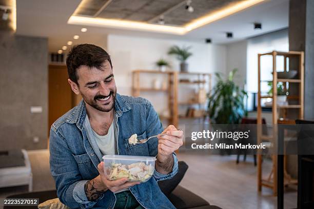 homme heureux mangeant une salade saine dans un récipient réutilisable à la maison - regarder vers le bas photos et images de collection