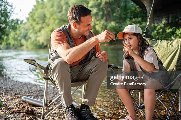 vater und tochter genießen das fliegenfischen am flussufer an einem sonnigen tag - angeln stock-fotos und bilder