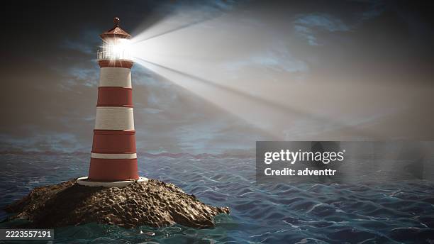 lighthouse standing on rocky island guiding ships under a dramatic cloudy sky - vuurtoren stockfoto's en -beelden