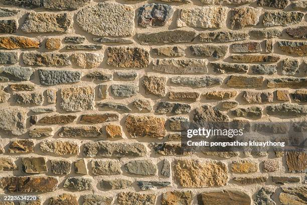front view of the exterior of a wall with stone blocks in the foreground without people around. - cobblestone stock pictures, royalty-free photos & images