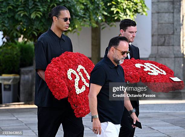 Virgil van Dijk and Andrew Robertson, football players for Liverpool FC, carry floral tributes which read "20" and "30" as they arrive with teammates...