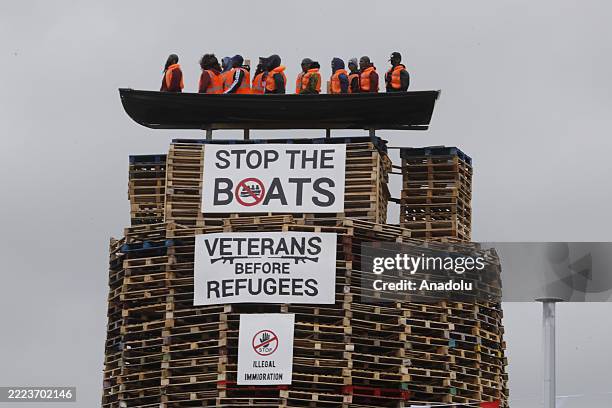 Bonfire structure featuring an effigy of refugees in a boat with banners reading "Stop the Boats" and "Veterans Before Refugees" is seen as the...