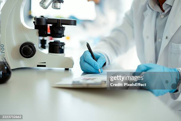 medical scientist analyzing data in clinical lab - microbiologie stockfoto's en -beelden