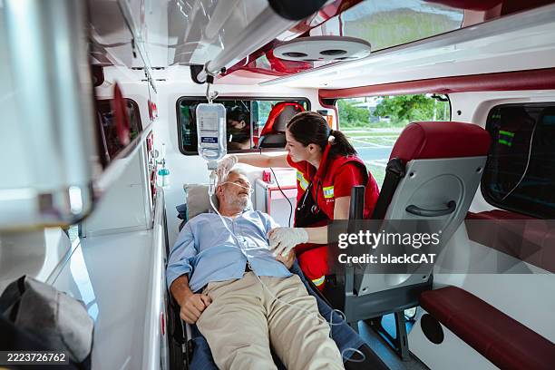 paramedic helping elderly patient inside ambulance during emergency - casualty stock pictures, royalty-free photos & images