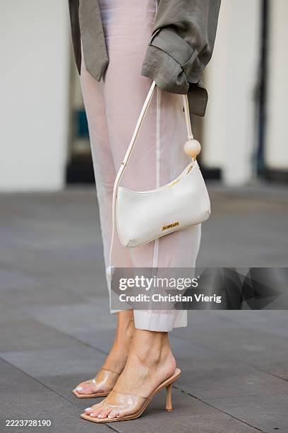 Tina Haase wears Frankie Shop khaki Short trench coat, white Zara transparent skirt, transparent vinyl heels, cream white Jacquemus baguette bag on...