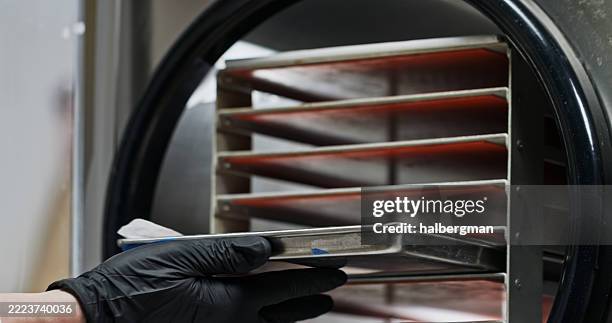 nahaufnahme des tabletts, das mit handschuhen in den gefriertrockner geladen wird - vakuumkammer stock-fotos und bilder